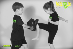 young girl kicking training pads with you boy helping