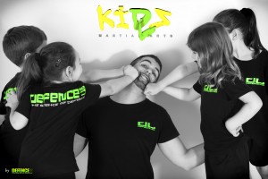 young children play fighting with instructor with logo